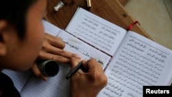 Seorang santri menulis dalam bahasa Arab ketika belajar Al-Quran di bulan Ramadan di pesantren Lirboyo di Kediri, 18 Mei 2018. 