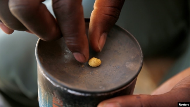An artisanal gold miner picks up a gold nugget at an unlicensed mine in Gaoua, Burkina Faso, Feb. 13, 2018.