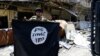 FILE - A member of the Emergency Response Division holds an Islamic State militants flag in the Old City of Mosul, Iraq, July 10, 2017. 