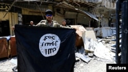 Anggota Divisi Tanggap Darurat memegang bendera militan ISIS di Kota Tua Mosul, Irak, 10 Juli 2017.