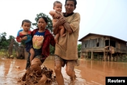 Parents carry their children as they leave their home during the flood after the Xe Pian Xe Namnoy hydropower dam collapsed in Attapeu province, Laos, July 26, 2018.