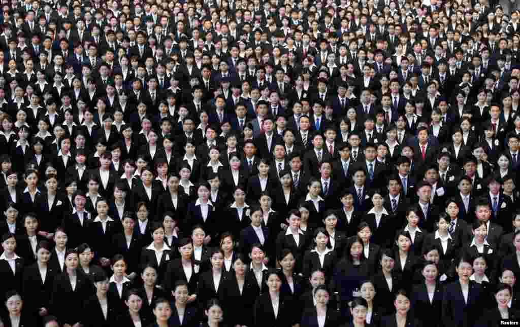 Newly-hired employees of Japan Airlines (JAL) group pose for photos during an initiation ceremony at a hangar of Haneda airport in Tokyo.