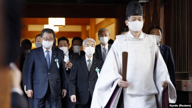 A Shinto priest accompanies a group of Japanese lawmakers as they visit the Yasukuni shrine to pay respects to the country's war dead in Tokyo, Japan, Dec. 7, 2021