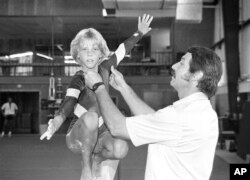 FILE - In this Aug. 12, 1985, photo, coach Bela Karolyi, right, instructs Sara Tank on the balance beam. When Tank arrived in Houston in 1985, she soon realized that the Bela Karolyi she had seen on television, who was "animated and acted like he loved kids," was "not the Bela that was in the gym." Sara Tank Ornelas said she suffered 13 broken bones while training in Houston from age 11 to 15.