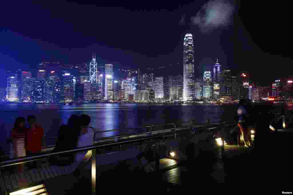 People rest along a waterfront at Hong Kong's Victoria Harbour facing the Hong Kong island side, China