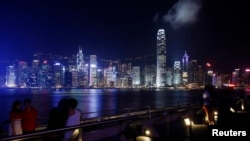 People rest along a waterfront at Hong Kong's Victoria Harbour facing the Hong Kong island side, China