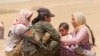 Displaced people from the minority Yazidi sect, fleeing violence from forces loyal to the Islamic State in Sinjar town, get help from a member of the YPG near the Syrian border.