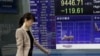 A woman walks by a securities' firm in Tokyo, Friday, Sept. 24, 2010. The Nikkei 225 stock average lost 1.3 percent to 9,446.71 in morning trading as Asian stock markets mostly fell Friday after a jump in U.S. unemployment claims provided more evidence of