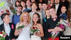 FILE - Two brides pose with their guests after their wedding ceremony at the wedding registry office in St. Petersburg, seemingly circumventing Russia's ban on same-sex marriages, Nov. 7, 2014. 
