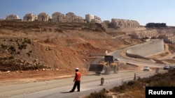 A laborer stands by a construction vehicle near the West Bank Jewish settlement of Beitar Illit, seen in this July 18, 2011, file photo. 