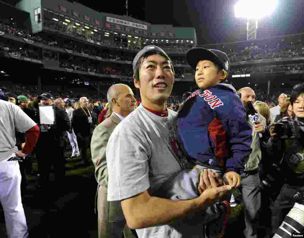 Boston Red Sox relief pitcher Koji Uehara (left) holds his son Kaz Uehara as they celebrate on the field after game six of the MLB baseball World Series against the St. Louis Cardinals at Fenway Park, Boston, Massachusetts.