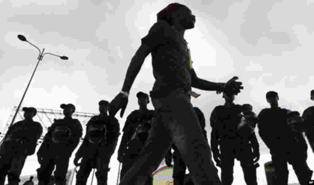 An Equatorial Guinea fan walks past Equatorial Guinea's police special forces standing at their positions at Estadio de Bata "Bata Stadium", which will host the opening match and ceremony for the African Nations Cup, in Bata January 21, 2012.