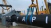 Workers stand near a gas pipe during the launching ceremony of construction work of the TAPI project on the Afghan section of a natural gas pipeline that will link Turkmenistan through Afghanistan to Pakistan and India, near the town of Serhetabat,Turkmenistan, Feb. 23, 2018.