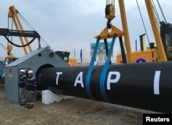 FILE - Workers stand near a gas pipe during the launching ceremony of construction work of the TAPI project on the Afghan section of a natural gas pipeline that will link Turkmenistan through Afghanistan to Pakistan and India, near the town of Serhetabat, Turkmenistan.