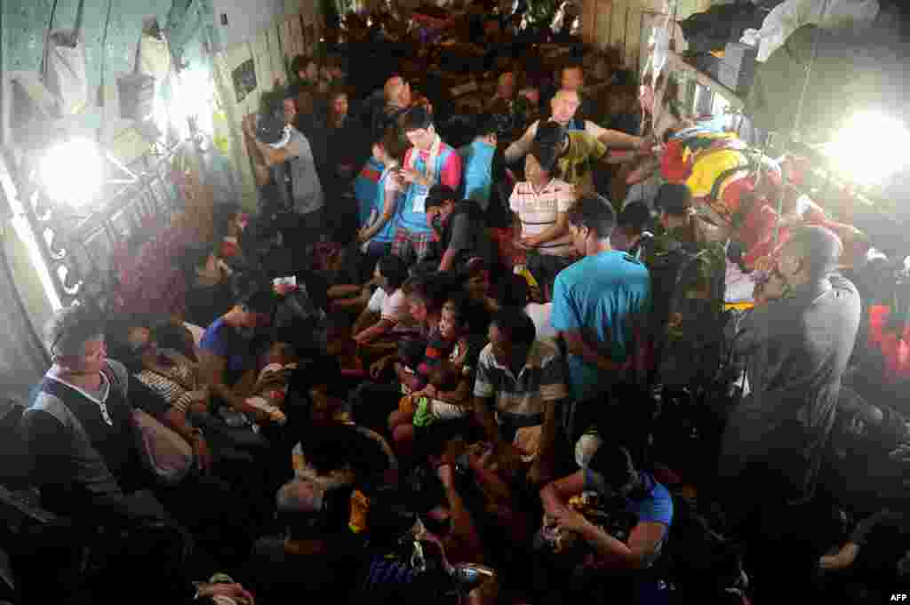 Typhoon survivors in the Philippines ride on board a C-130 military plane out of Tacloban, Leyte province, to Manila.