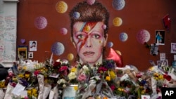 Tributes lie placed around a mural of British singer David Bowie by artist Jimmy C in Brixton, south London, Thursday, Jan. 14, 2016. 