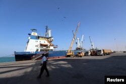 FILE - A coast guard member walks past a ship docked at the Red Sea port of Hodeida, Yemen, Jan. 5, 2019.