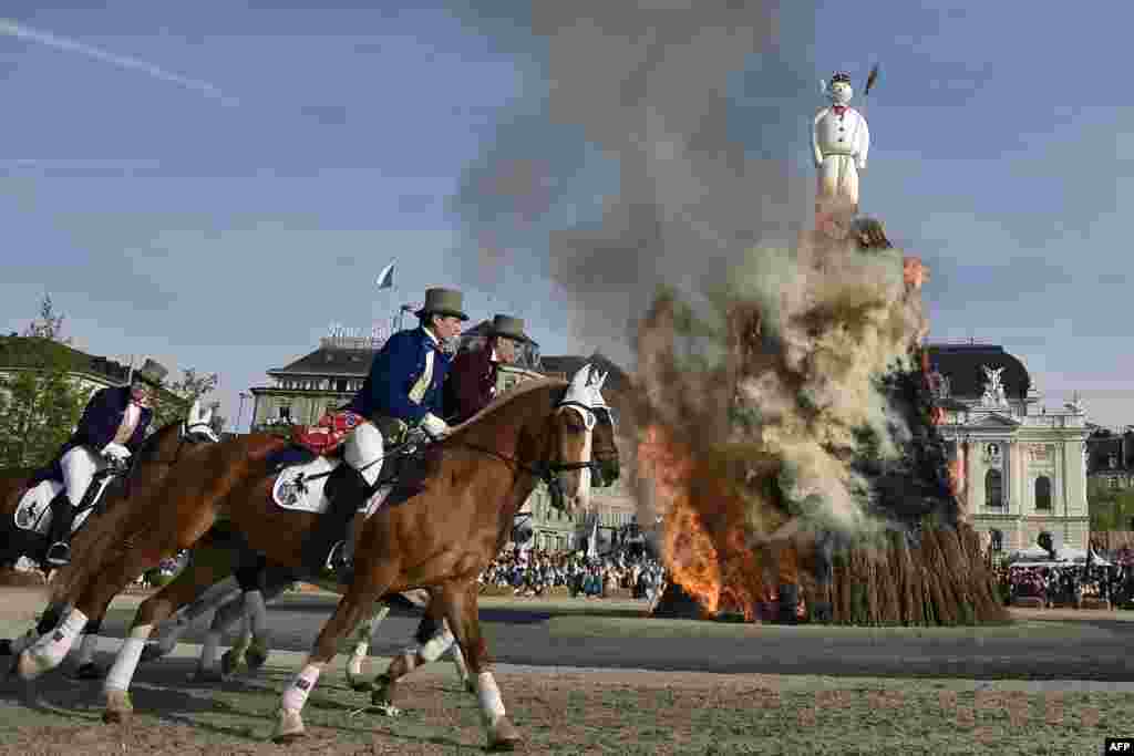 Members of a guild ride around the Boeoegg, a giant symbolic snowman made of wadding and and filled with firecrackers burning on top of a bonfire in Sechselaeuten square in Zurich.