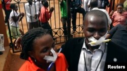Employees of the Daily Monitor newspaper with their mouths taped shut, sing slogans during a protest against the closure of their premises by the Uganda government, outside their offices in the capital Kampala, Uganda, May 20, 2013.