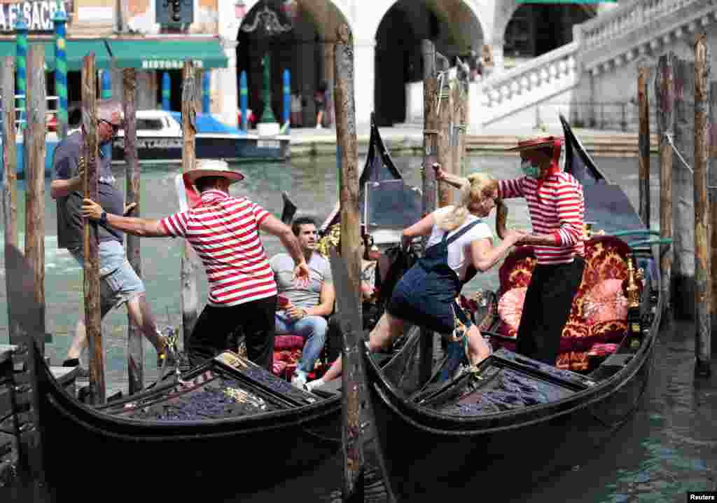 Gondolijeri pomažu turistima da se popnu na gondole, dok region Veneto postaje tzv. &quot;bela zona&rdquo; nakon svođenje ograničenja zbog kovida -19 na korišćenje maske i socijalno distanciranje. Venecijia, &nbsp;7. juni, 2021. ( Foto: Jara Nardi / Rojters )