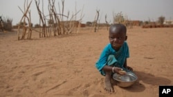 FILE - А boy is seen eating dry couscous in the village of Goudoude Diobe, in the Matam region of northeastern Senegal.