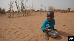 FILE - А boy is seen eating dry couscous in the village of Goudoude Diobe, in the Matam region of northeastern Senegal.