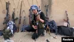 FILE - A female Kurdish fighter from Kurdish People's Protection Units (YPG) checks her weapon near Ras al-Ain, in the Syrian province of Hasakah, after capturing it from Islamist rebels November 6, 2013. 