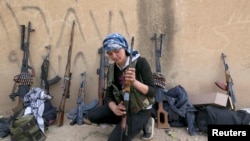 FILE - A female Kurdish fighter from Kurdish People's Protection Units checks her weapon near Ras al-Ain, in the Syrian province of Hassakeh, after capturing it from Islamist rebels on November 6, 2013. 