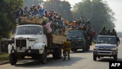 Un véhicule de la police passe à côté des camions transportant des musulmans voyageant pour Bangui, Centrafrique, 17 janvier 2014. 