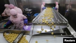 Employees work at a production line prior to a seizure conducted by officers from the Shanghai Food and Drug Administration, at the Husi Food factory in Shanghai, July 20, 2014. 
