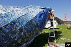 Project manager Meredith Winner looks over a blue whale art piece made from discarded single-use plastic being put together at Crissy Field in San Francisco, Oct. 12, 2018.