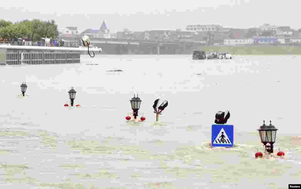 A traffic sign and the tips of street lamps are seen in floodwaters as a riverside street is submerged by an overflowing river after heavy rainfalls hit Lanxi, Zhejiang province, China, June 22, 2014.