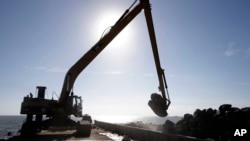 Una excavadora recoge rocas de una barca en el Golfo de México, donde se restaura un arrecife de ostras.