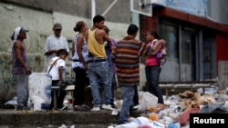FILE - People search through the garbage on a street in Caracas, Venezuela, Nov. 30, 2016. As the economy suffers, some Venezuelans have been forced to forage for food.