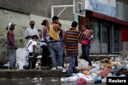FILE - People search through the garbage on a street in Caracas, Venezuela, Nov. 30, 2016. As the economy suffers for a third year, some Venezuelans are forced to forage for food.