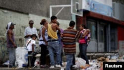 FILE - People search through the garbage on a street in Caracas, Venezuela, Nov. 30, 2016. As the economy suffers, some Venezuelans are forced to forage for food.