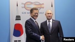 Presiden Rusia Vladimir Putin (kanan) berjabat tangan dengan Presiden Korea Selatan Moon Jae-in dalam sebuah pertemuan di sela-sela KTT G20 di Hamburg, Jerman, 7 Juli 2017. (Sputnik/Mikhail Klimentyev/Kremlin via REUTERS)