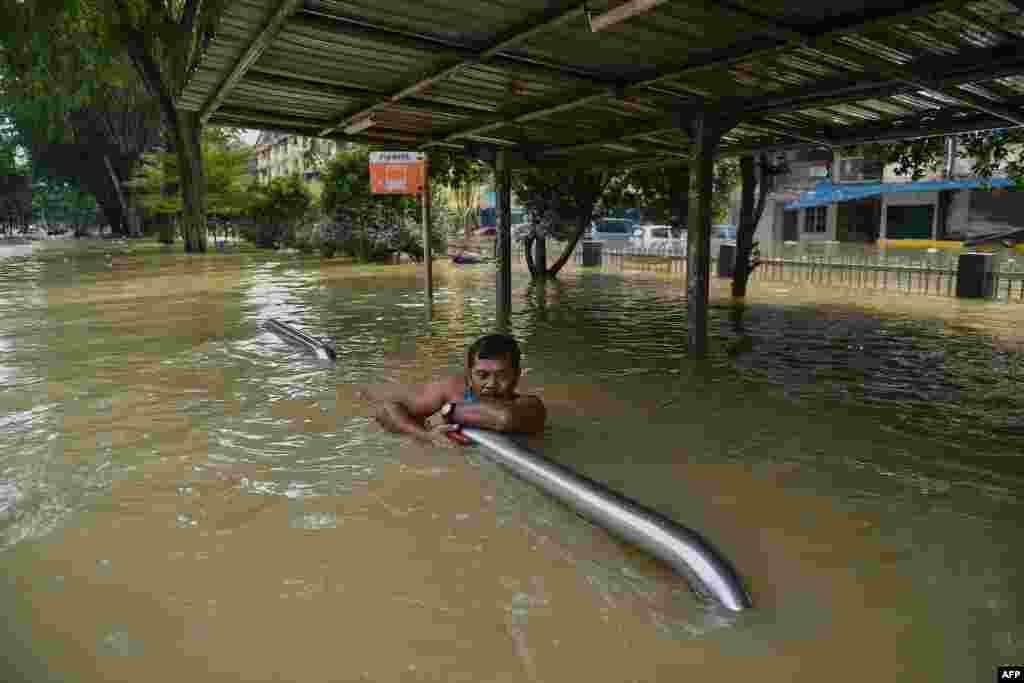 A man holds onto barriers as he waits to be evacuated by a rescue team in Shah Alam, Selangor, as Malaysia faces some of its worst floods for years.