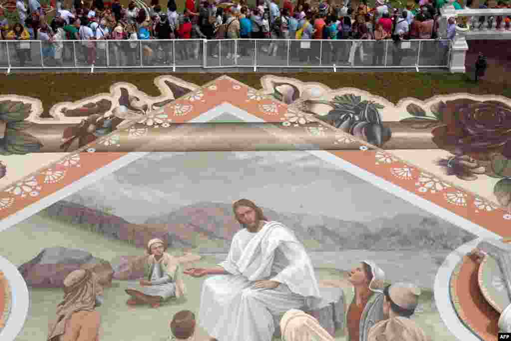 Visitors look at a carpet made from sand from the National Park of El Teide depicting Jesus preaching during the Corpus Christi Feast, in the town of La Orotava, on the Spanish Canary Island of Tenerife.