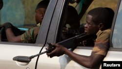 A former Seleka soldier holds his weapon as he keeps guard from a vehicle during an operation of transferring all former Seleka soldiers from their main base Camp de Roux to a smaller base in the north of the capital Bangui on January 27, 2014. 