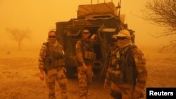 FILE - French soldiers from Operation Barkhane stand outside their armored personnel carrier during a sandstorm in Inat, Mali, May 26, 2016. 