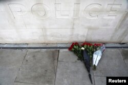 FILE - Flowers are left outside New Scotland Yard after a minute's silence the morning after an attack by a man driving a car and wielding a knife left five people dead and dozens injured, in London, March 23, 2017.