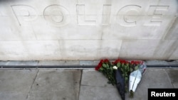 FILE - Flowers are left outside New Scotland Yard after a minute's silence the morning after an attack by a man driving a car and wielding a knife left five people dead and dozens injured, in London, March 23, 2017.