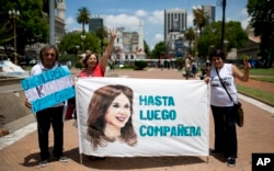 FILE - Government supporters hold a banner that reads in Spanish "See you soon colleague" featuring an image of President Cristina Fernandez in Buenos Aires, Argentina, Dec. 9, 2015.