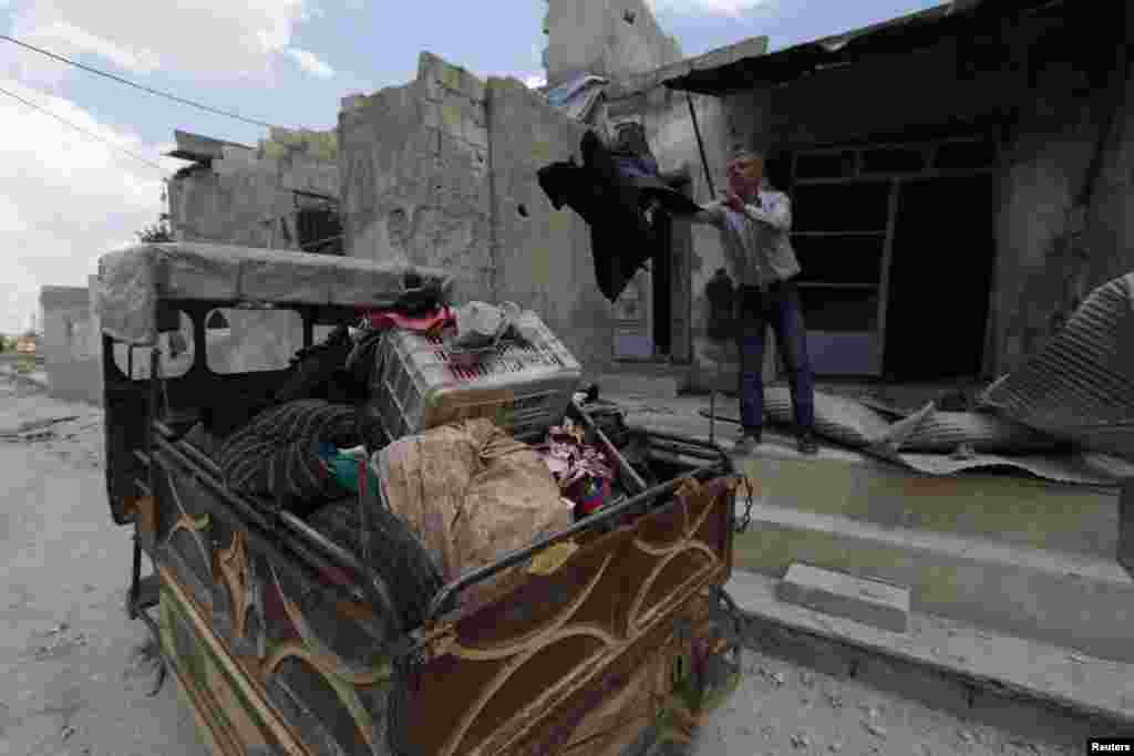 A man puts his belongings in the back of a vehicle at a site hit by what activists said were barrel bombs dropped by forces loyal to President Bashar al-Assad, Baaideen neighborhood, in Aleppo, May 23, 2014.