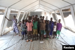 FILE - Children who fled fighting in South Sudan pose for a photograph inside a tented classroom at Bidi Bidi refugee’s resettlement camp near the border with South Sudan, in northern Uganda Dec. 7, 2016.