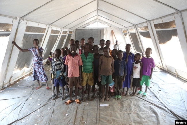 FILE - Children who fled fighting in South Sudan pose for a photograph inside a tented classroom at Bidi Bidi refugee’s resettlement camp near the border with South Sudan, in northern Uganda Dec. 7, 2016.