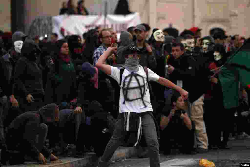 Manifestante arremessa pedras contra o cordão policial
