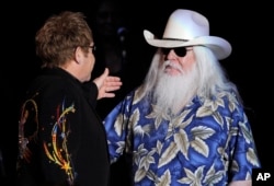 FILE - Elton John, left, greets Leon Russell on the stage during their joint concert at the Hollywood Palladium in Los Angeles, Nov. 3, 2010.