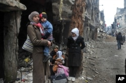 FILE - Residents of the besieged Yarmouk Palestinian refugee camp wait to leave the camp, on the southern edge of the Syrian capital Damascus, Syria, in this Feb. 4, 2014, photo released by the Syrian official news agency SANA.